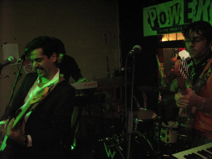 three young men play guitar as they perform in a band