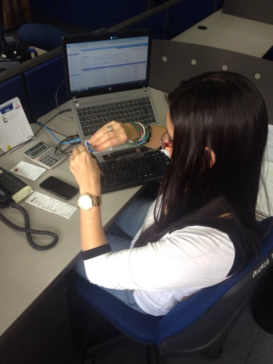 a woman sitting at a desk with a laptop computer and mouse