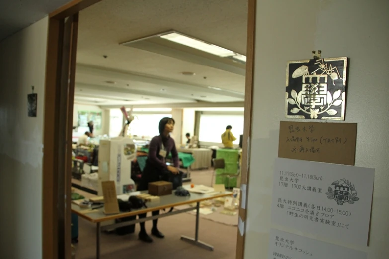 a woman walks in an office with many sticky notes on the wall