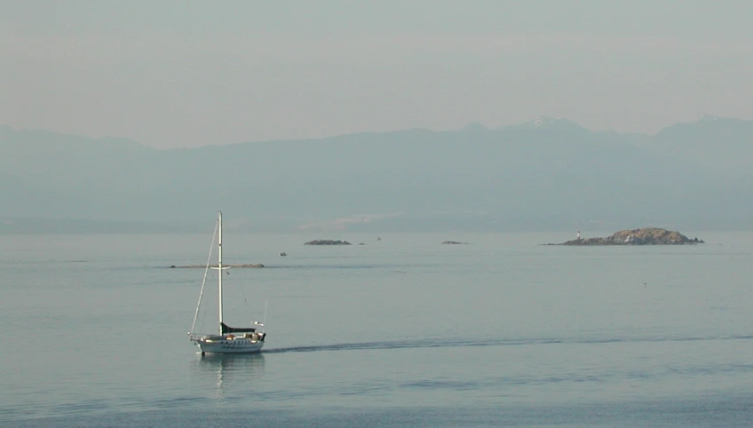 a sailboat traveling on water with mountains in the background