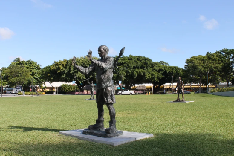 a statue in the middle of a park holding his hands up