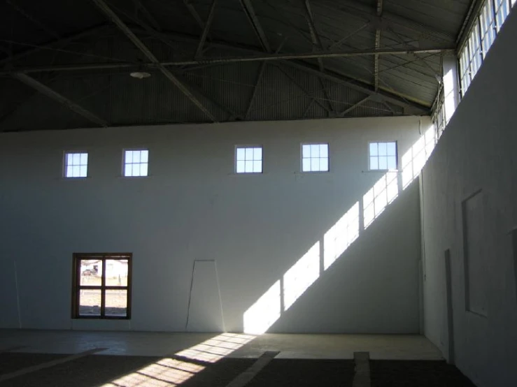 sunlight shines through three windows in an empty building