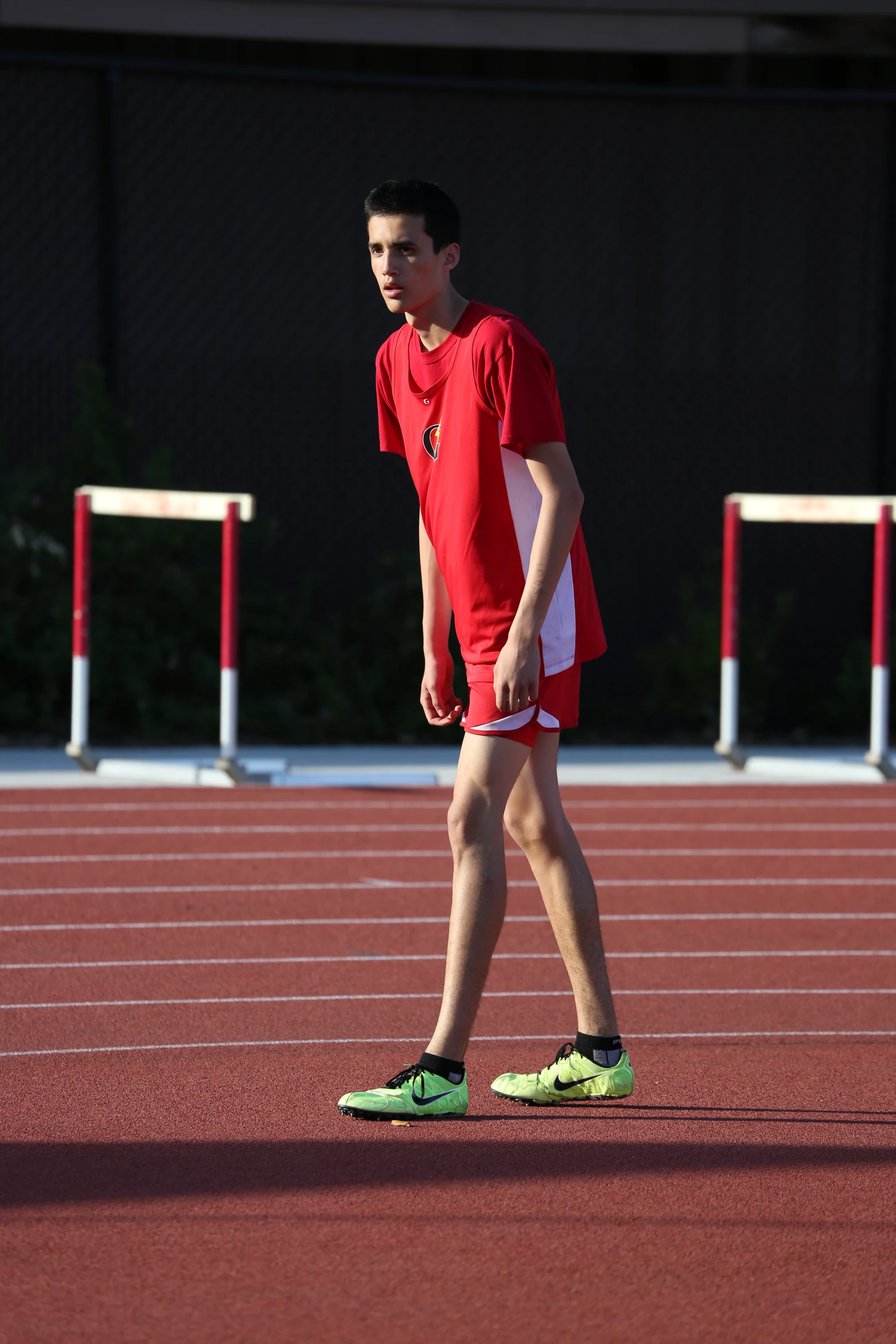 a young male in a bright red t - shirt and a pair of shoes