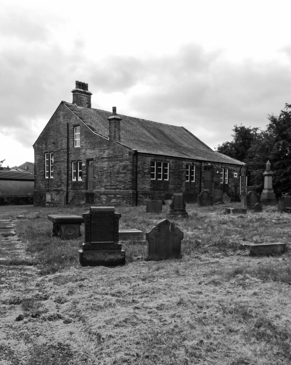 an old brick building with several graves in the yard