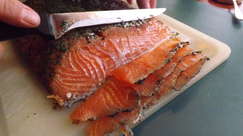 someone chopping up some salmon with a sharp knife