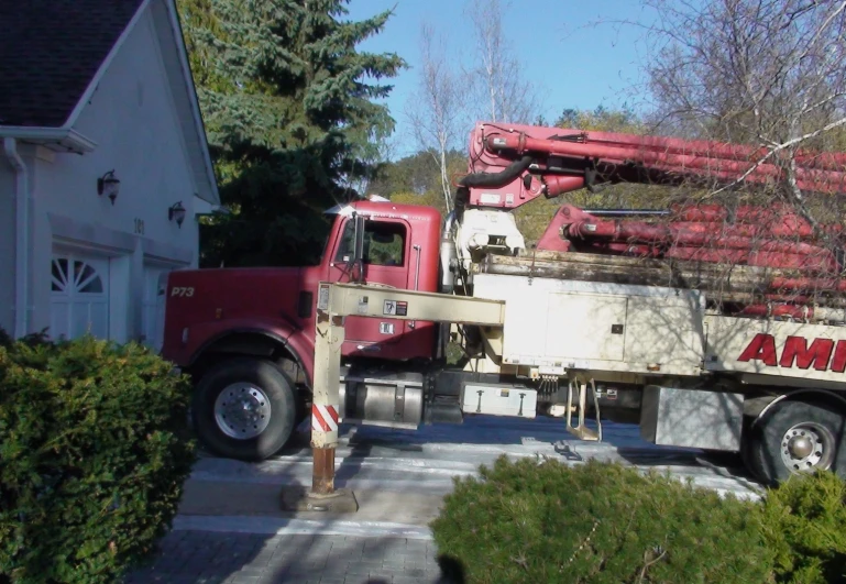 a red truck parked on top of a sidewalk next to a house