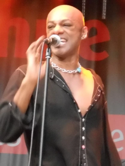 an african american male in a black shirt singing into a microphone