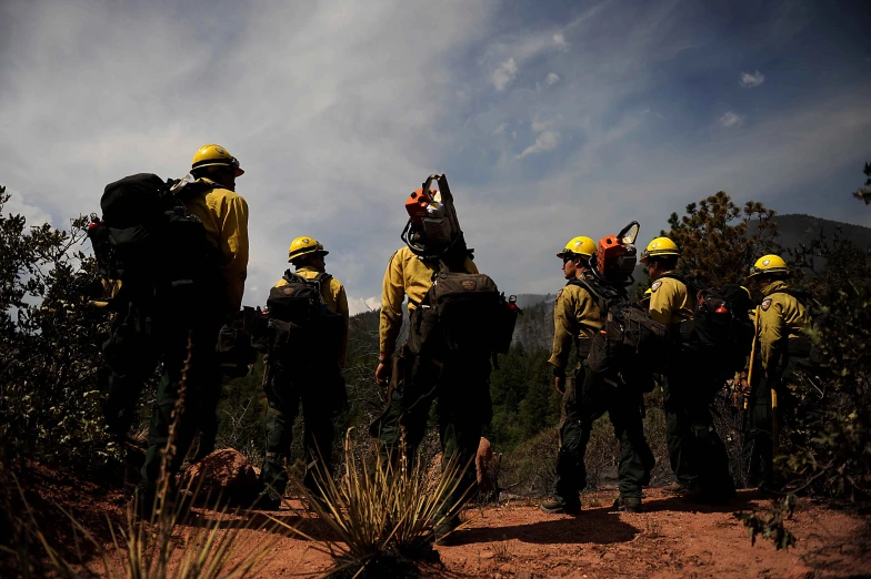 a group of firefighters with helmets on looking over the mountain side