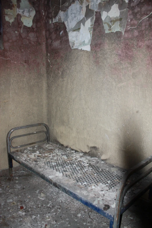 an old wrought iron daybed against a dirty wall