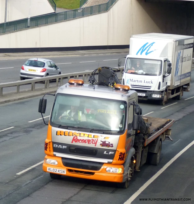 an orange and white truck pulling a yellow load