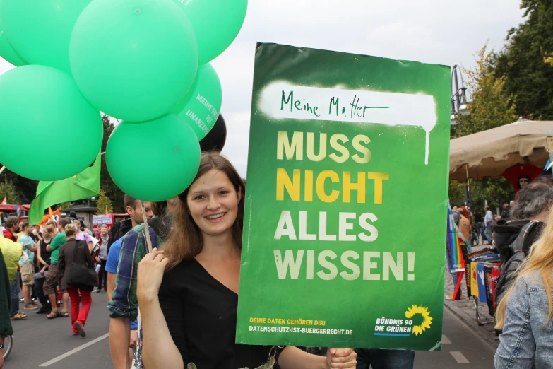 a woman with a green sign holding up some balloons