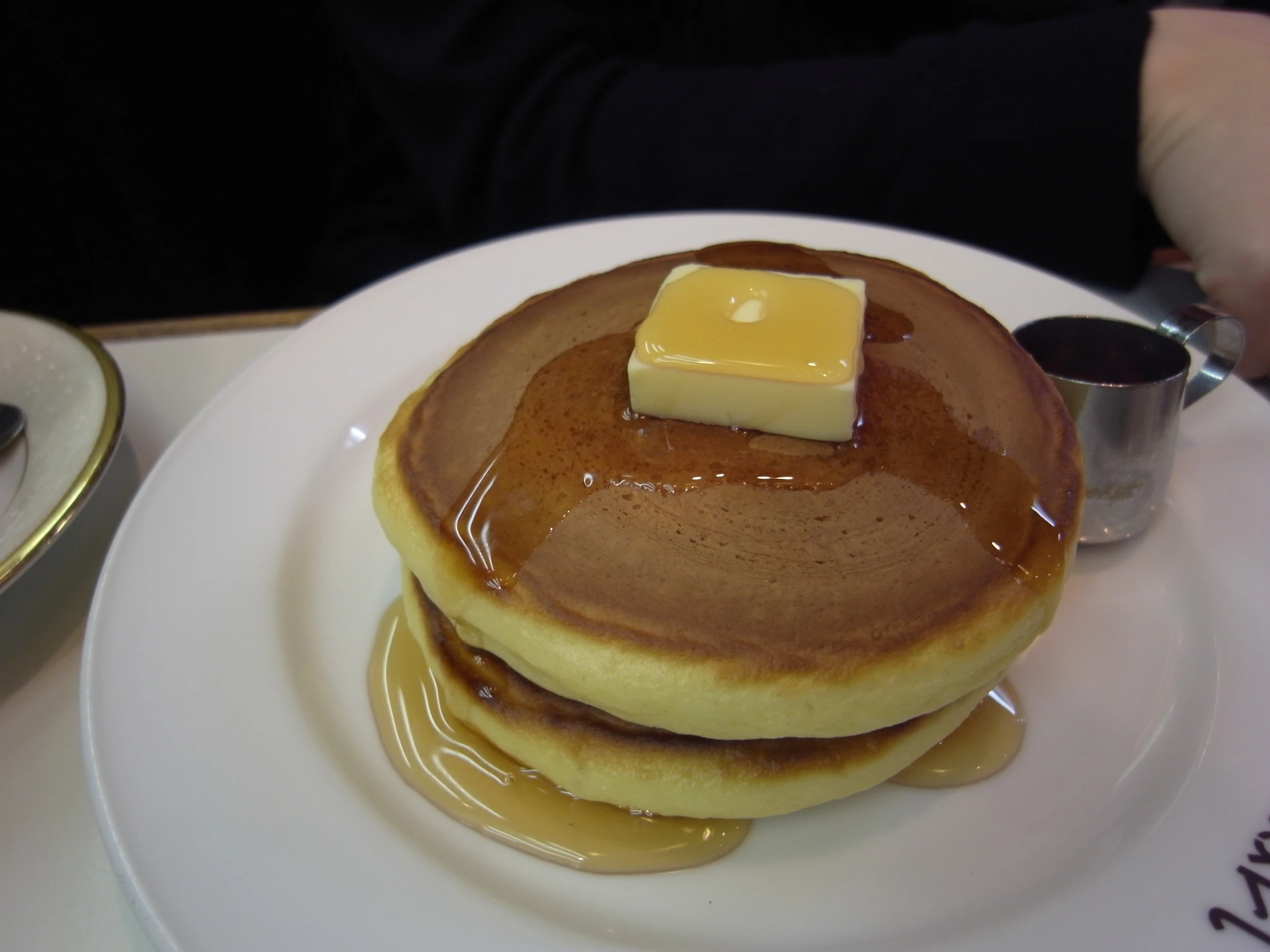 pancakes on a white plate with er and syrup on top