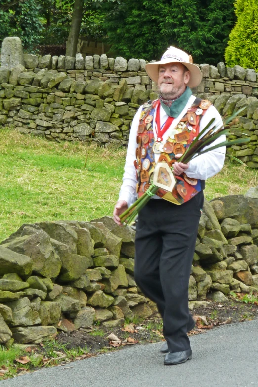 an older man is walking along the road with flowers in hand