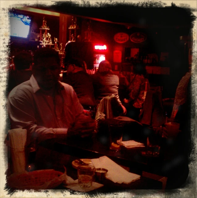 a man sitting in the bar while another person is serving food