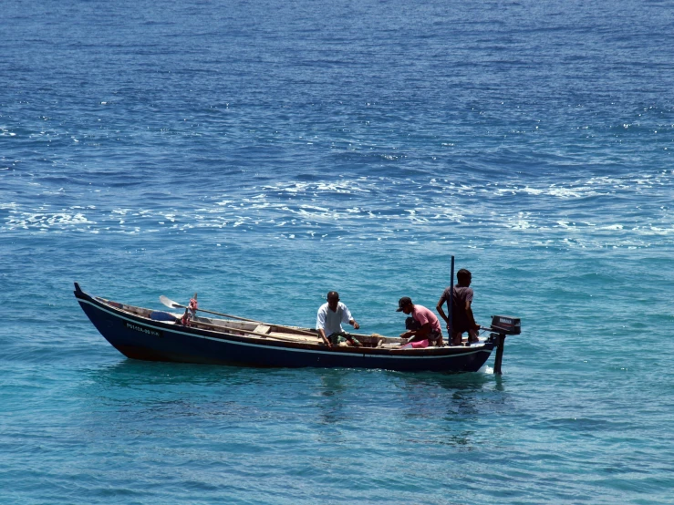 four people in a small blue boat on the water