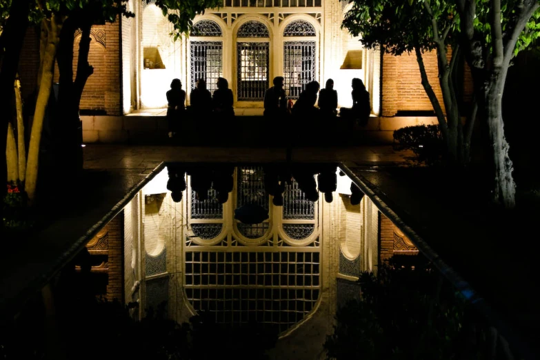 some people sitting at the end of a pool while the lights shine on them