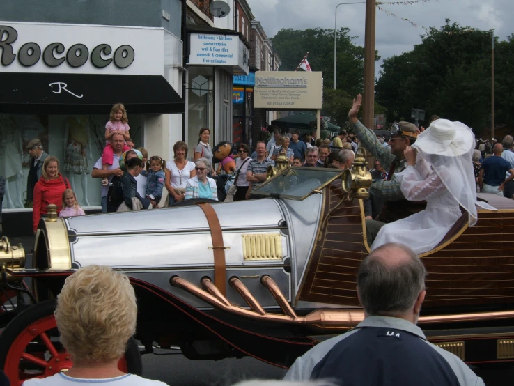 a large crowd is in a town by a car