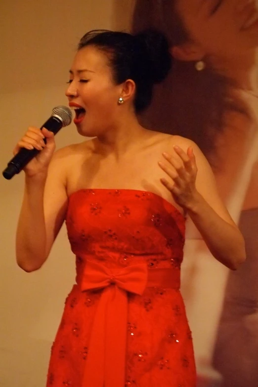 woman in red dress holding a microphone up to her ear