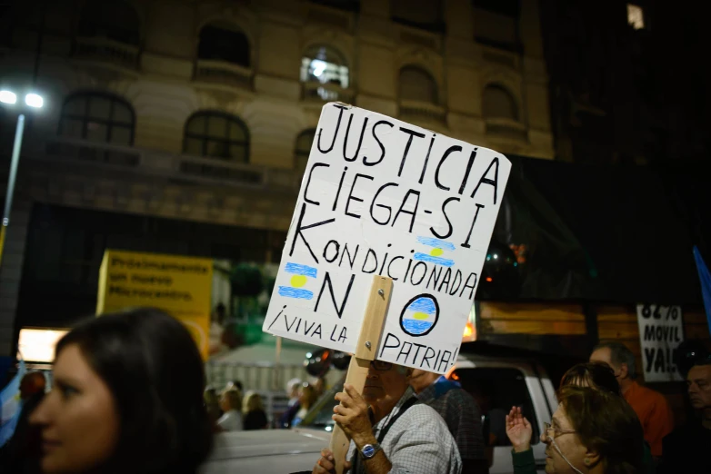 people standing outside at night holding up protest signs