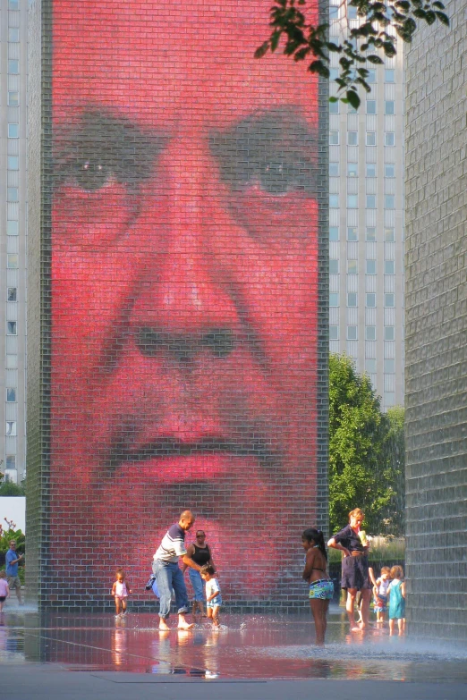 people gather in the plaza around a giant portrait