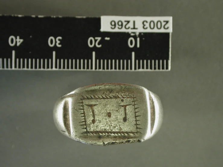 an antique silver object with a ruler next to it