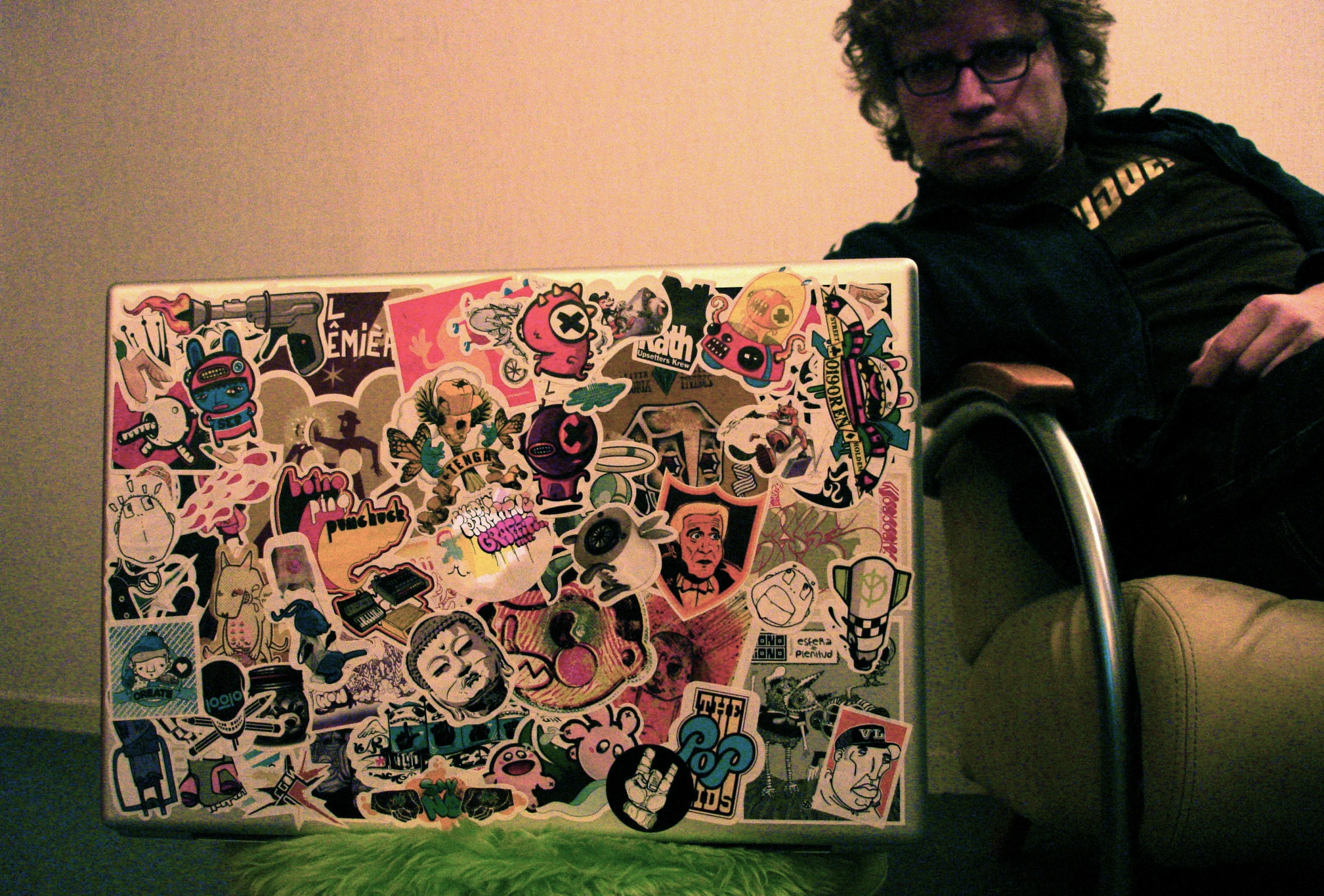 a man sits next to an artistic sticker laptop