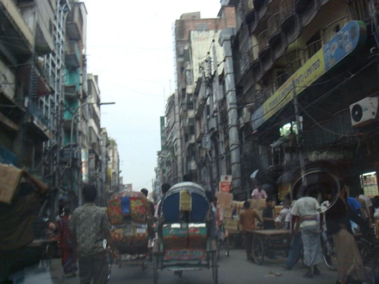 a rickshaw being ridden down the road while people stand in front of it