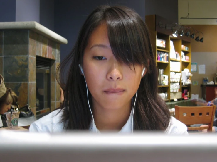 a woman with headphones on is staring over her laptop