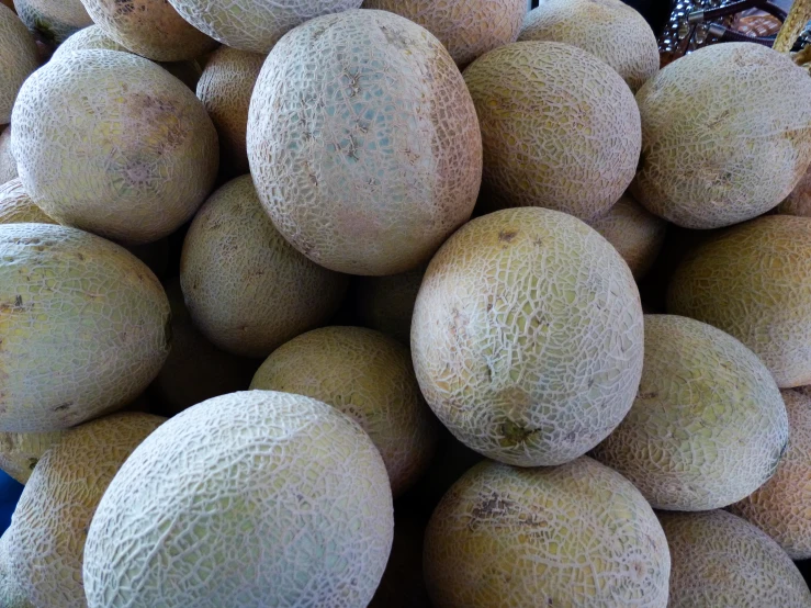 a pile of melons on display for sale at a market