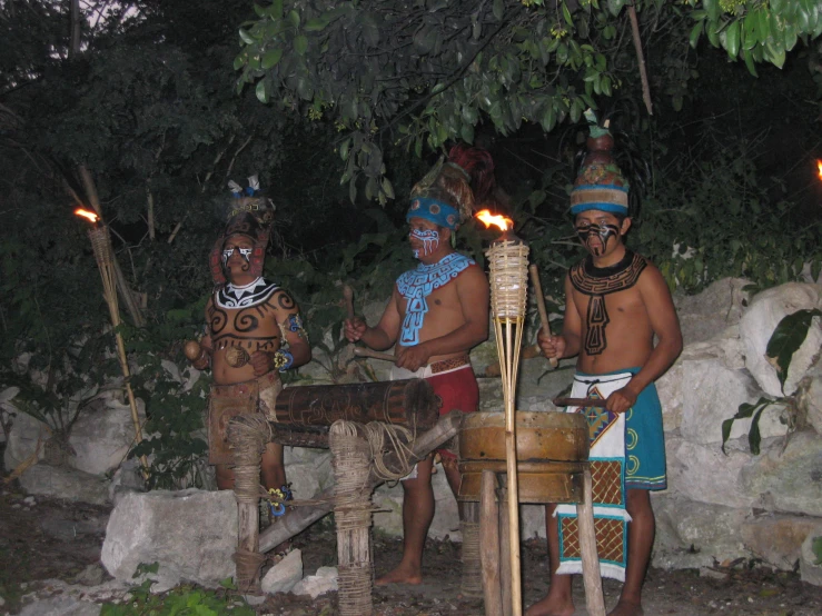 four men in costumes are holding torches next to an elephant