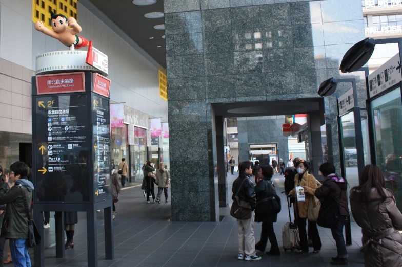 people stand outside of a shopping mall where there are signs for stores