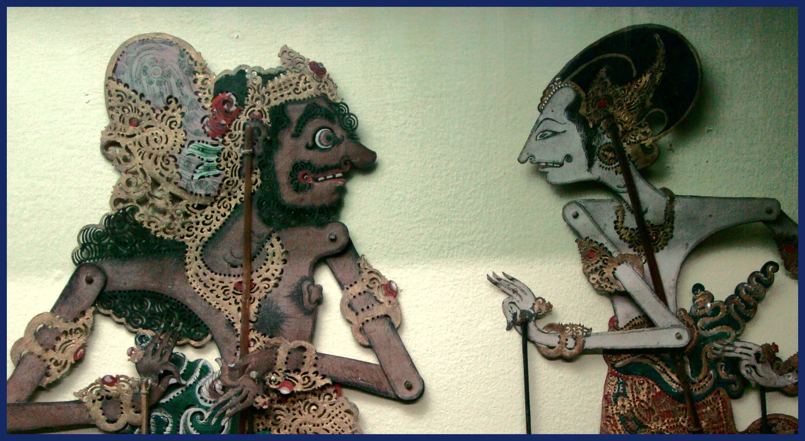 two paper dolls made from scrap, one is holding a knife