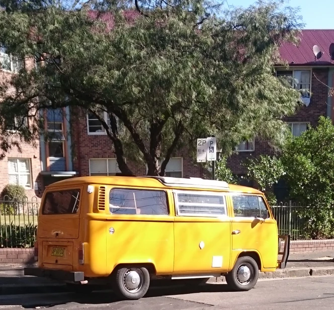 yellow and black vw van parked next to tree