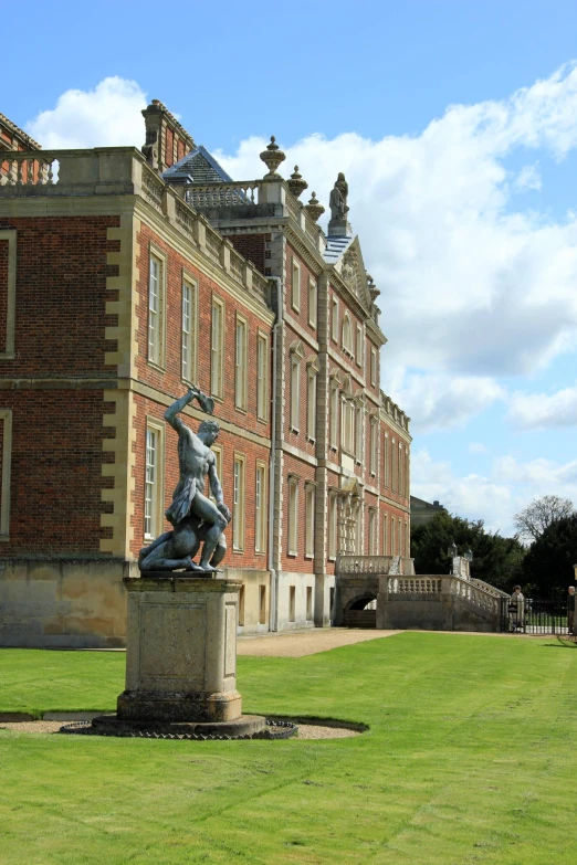 a statue in a grassy area in front of a large building