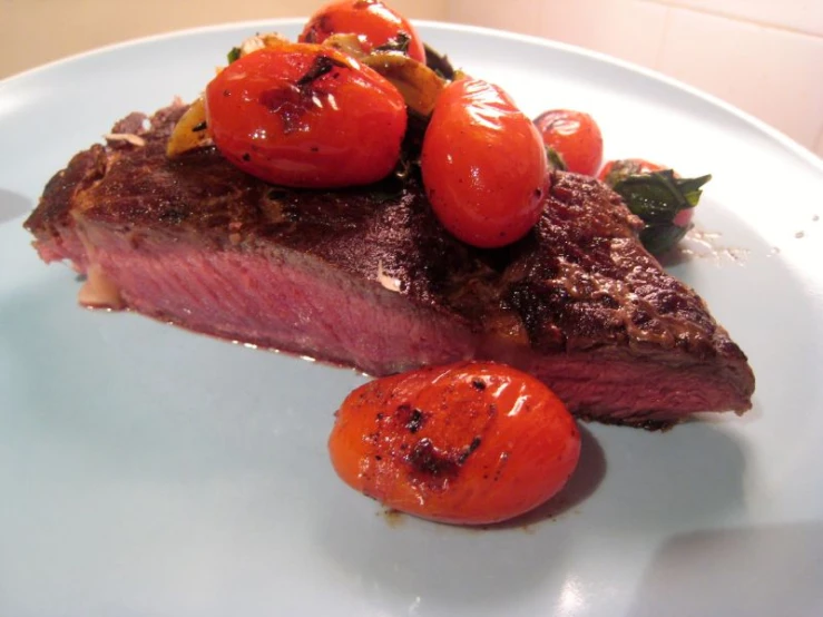 a white plate topped with meat and tomatoes