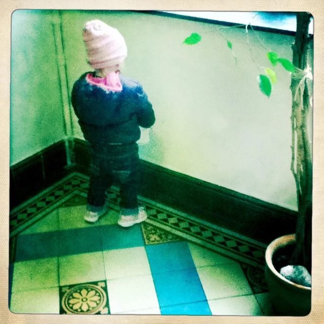 a small child with a pink hat looking down at a tree