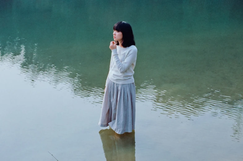 a girl standing in water with her hands to her face