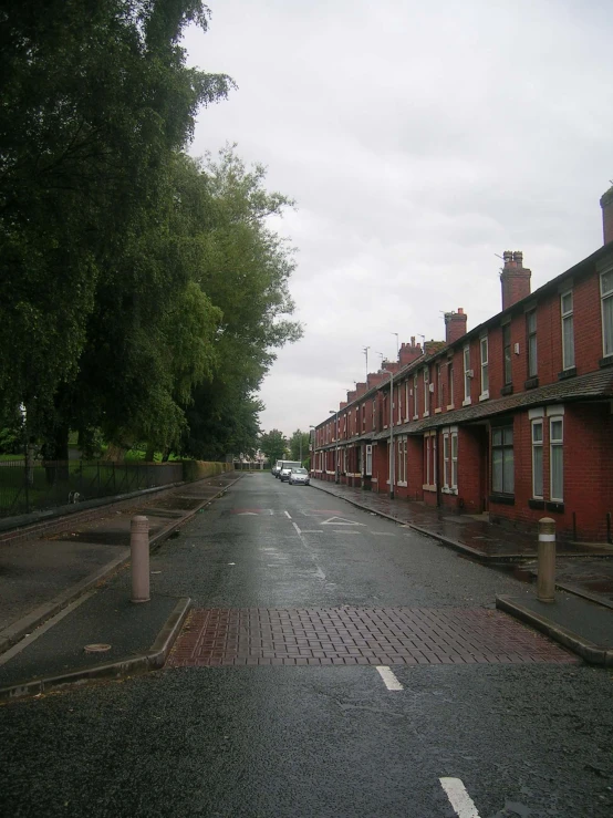 a wet sidewalk near a row of identical red brick houses