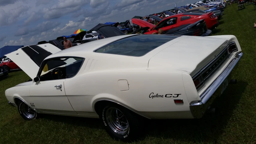 a classic car with the hood up parked in a grassy field