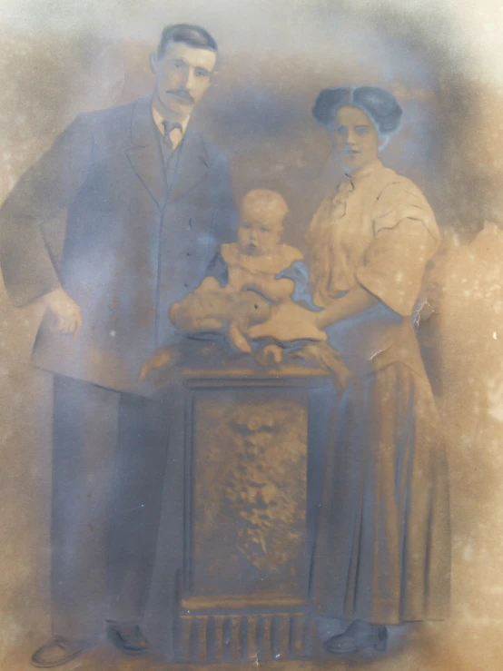 old pograph of family standing near baby in antique box