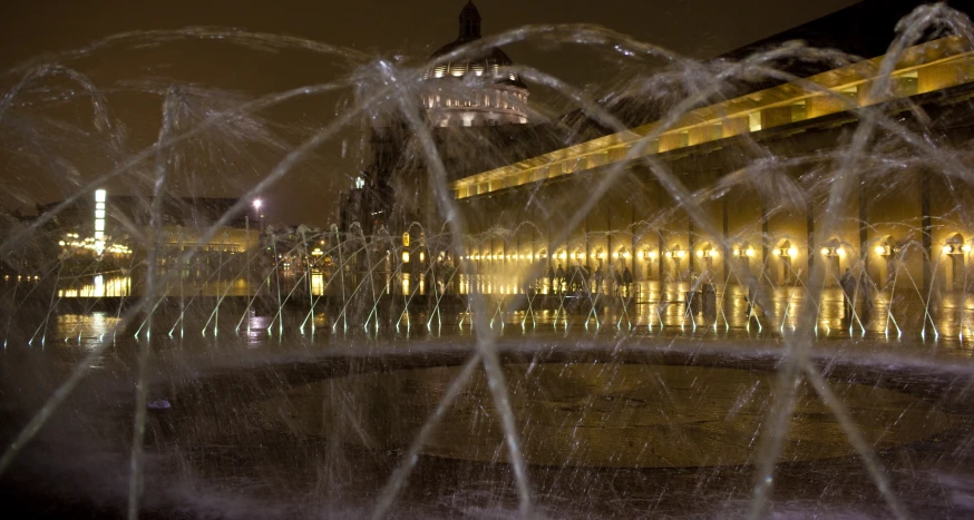 a fountain near a building with many lights behind it