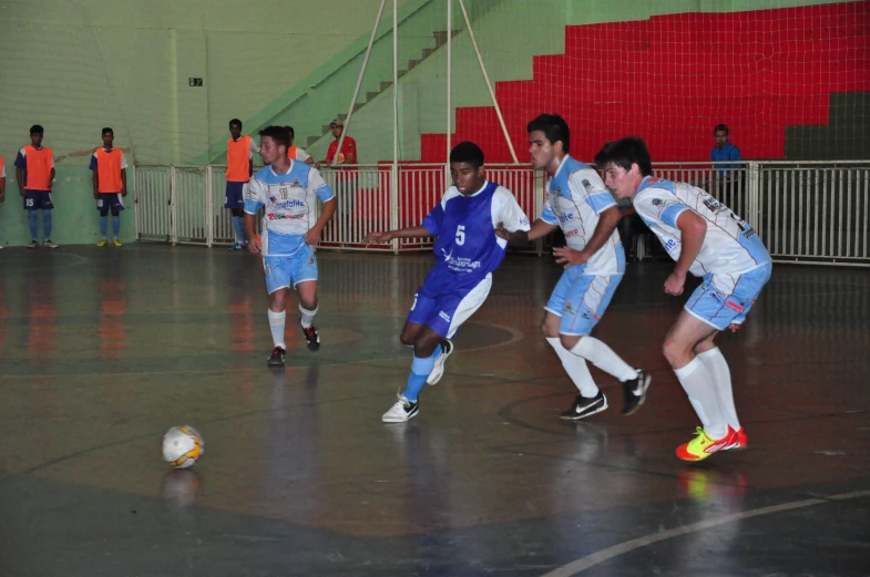 several young men playing soccer on an indoor field