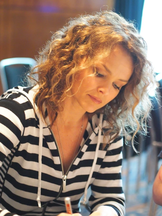 a young woman is sitting and looking down at her cellphone