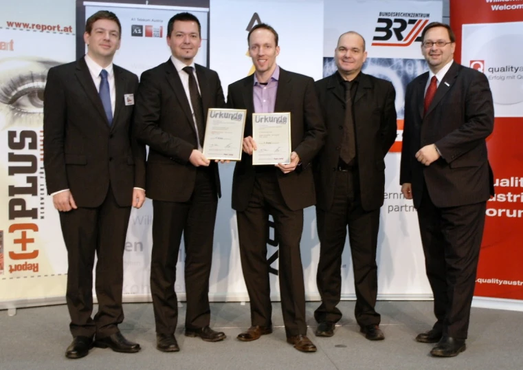 five men in suits and ties standing near a sign