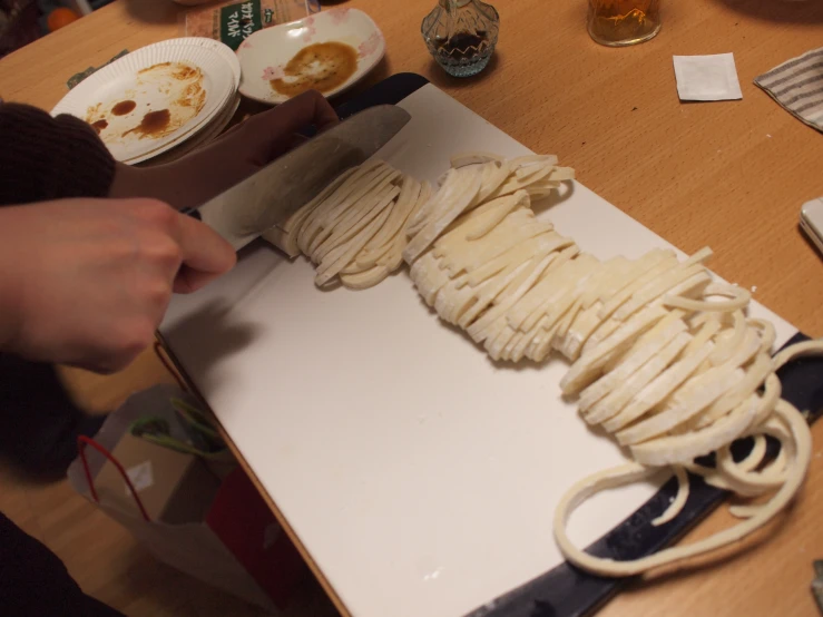 a hand is placing noodles into a baking box