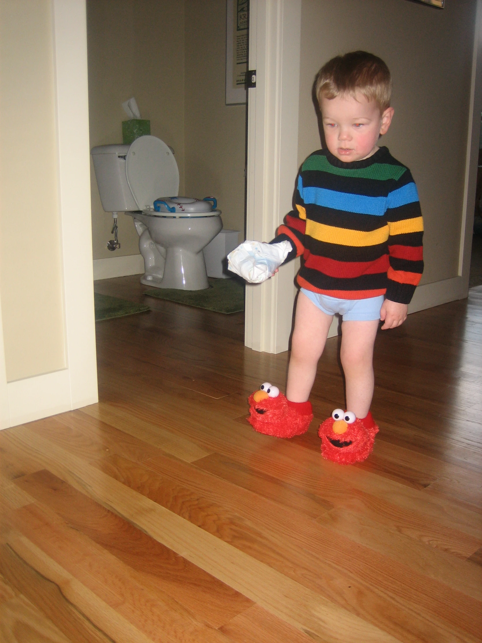 a small boy wearing a colorful striped shirt standing on a hard wood floor