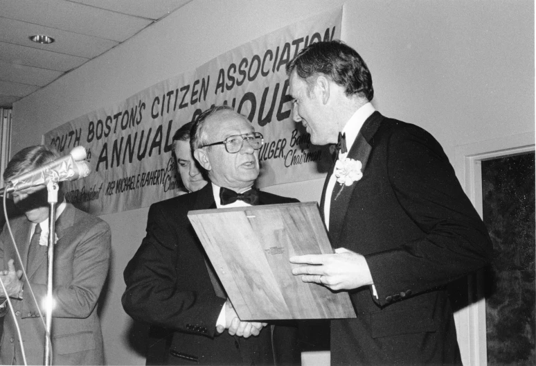 two men in tuxedos standing together and shaking hands