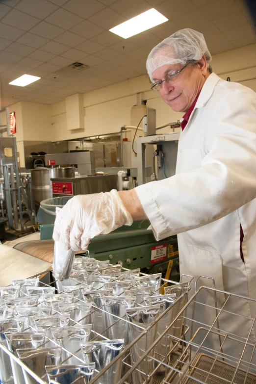 an older person in a lab putting glasses into a container