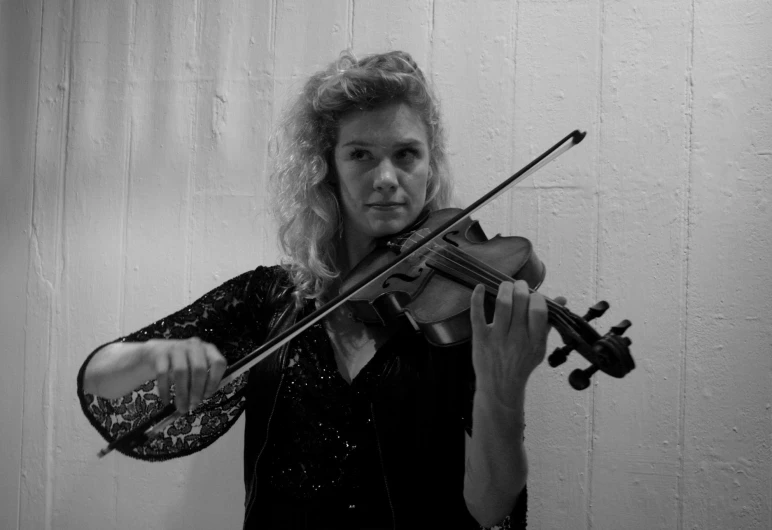 woman with long curly hair playing a violin