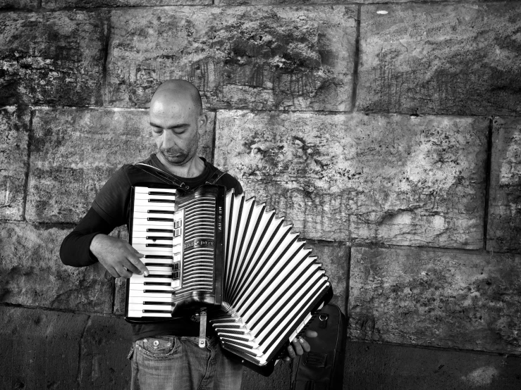 a man holding up an accordion next to a wall